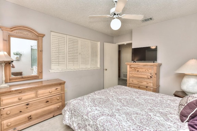 carpeted bedroom featuring visible vents, a textured ceiling, and ceiling fan