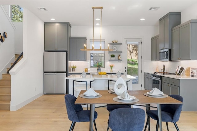 dining space featuring light wood finished floors, visible vents, stairs, recessed lighting, and an inviting chandelier