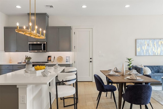 dining area with light wood finished floors, visible vents, recessed lighting, and a chandelier