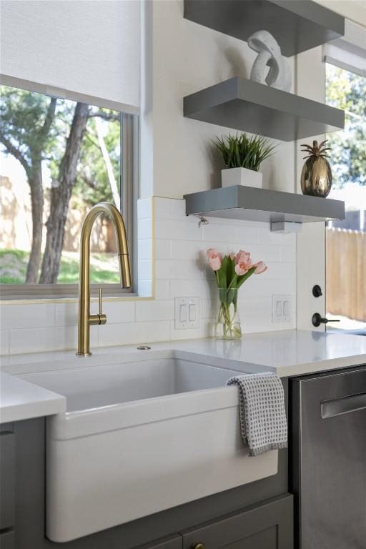 interior space featuring open shelves, a sink, light countertops, stainless steel dishwasher, and backsplash