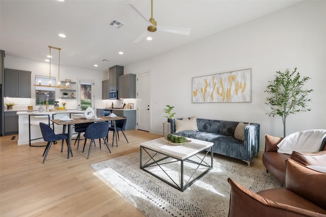 living room featuring recessed lighting, visible vents, light wood-style flooring, and ceiling fan with notable chandelier