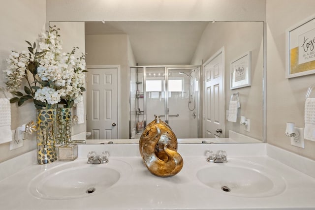 bathroom with a sink, a stall shower, and double vanity