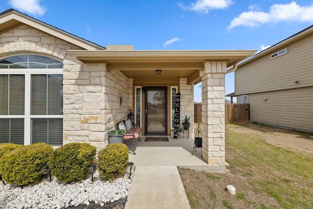 entrance to property with stone siding and fence