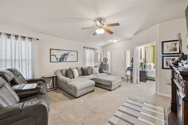 living area featuring a glass covered fireplace, plenty of natural light, light colored carpet, and vaulted ceiling