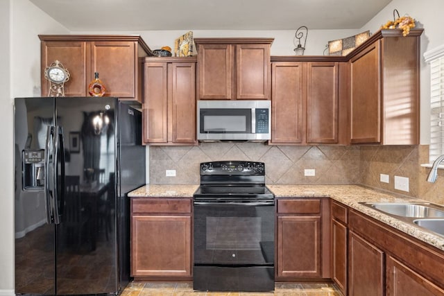 kitchen featuring tasteful backsplash, black appliances, light stone counters, and a sink