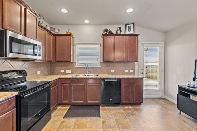 kitchen featuring tasteful backsplash, vaulted ceiling, light stone counters, black appliances, and a sink