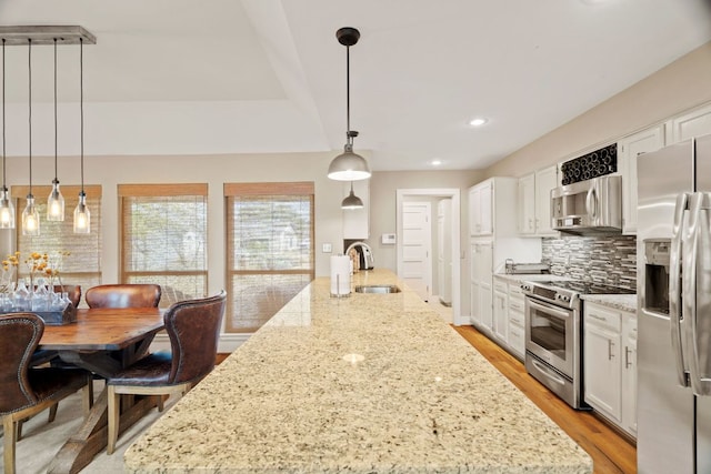 kitchen featuring a sink, backsplash, stainless steel appliances, light wood-style floors, and white cabinets