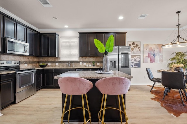 kitchen featuring visible vents, backsplash, stainless steel appliances, light wood-style floors, and light stone countertops