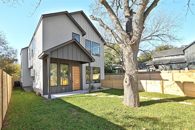 back of property with a lawn, board and batten siding, and a fenced backyard