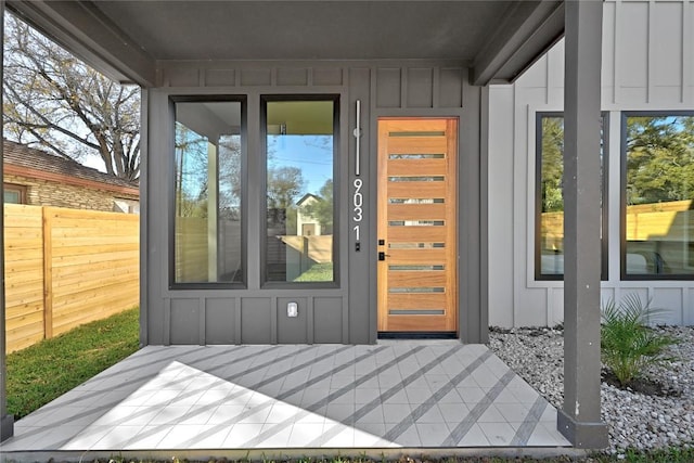 doorway to property featuring board and batten siding and fence