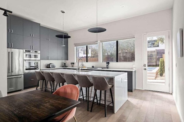 kitchen with a center island with sink, stainless steel appliances, a kitchen bar, and a sink