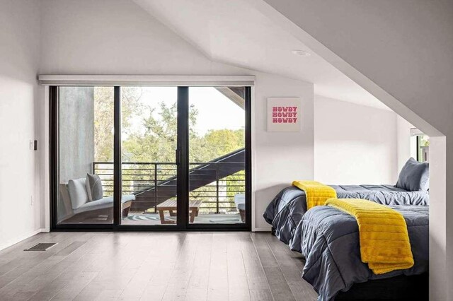 bedroom with lofted ceiling, wood finished floors, access to exterior, and visible vents