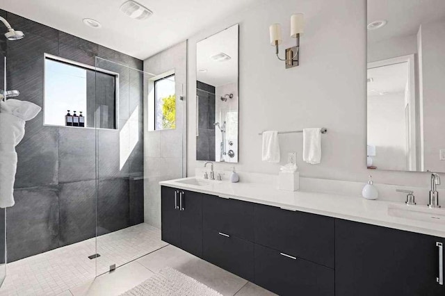 bathroom with a sink, tiled shower, double vanity, and tile patterned floors