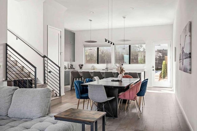 dining area featuring stairway, baseboards, and light wood finished floors