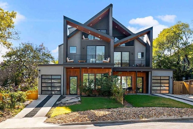 contemporary house with a balcony, an attached garage, and fence