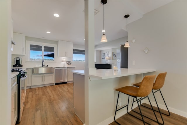 kitchen featuring a breakfast bar, light wood-style flooring, appliances with stainless steel finishes, white cabinets, and a sink