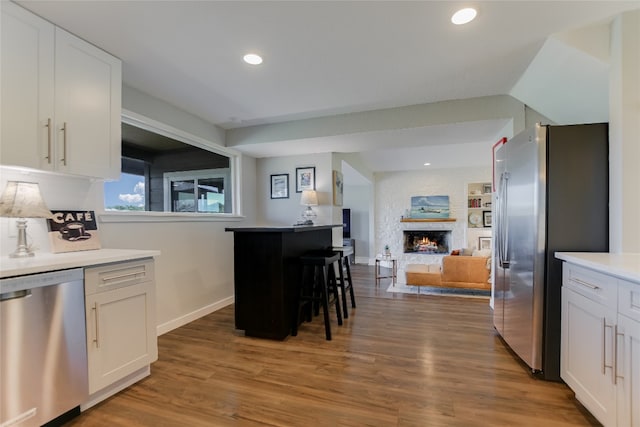 kitchen featuring a large fireplace, appliances with stainless steel finishes, open floor plan, and white cabinets