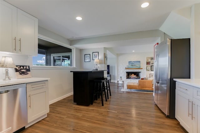8603 Appalachian Dr, Austin, TX 78759 - kitchen with appliances with stainless steel finishes, open floor plan, white cabinets, a large fireplace, and recessed lighting
