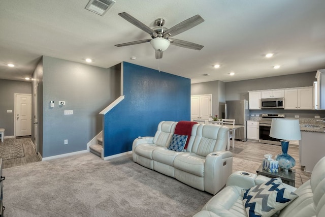 living area with recessed lighting, visible vents, baseboards, and stairway