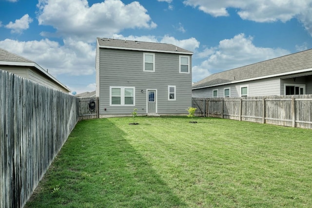 rear view of house with a yard and a fenced backyard