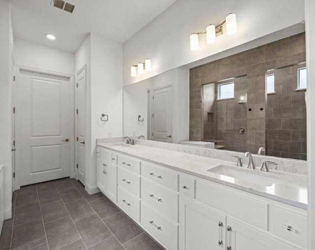 bathroom featuring a sink, visible vents, double vanity, and a walk in shower