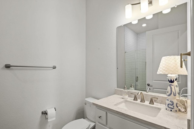 full bathroom featuring vanity, a shower stall, toilet, and a textured wall