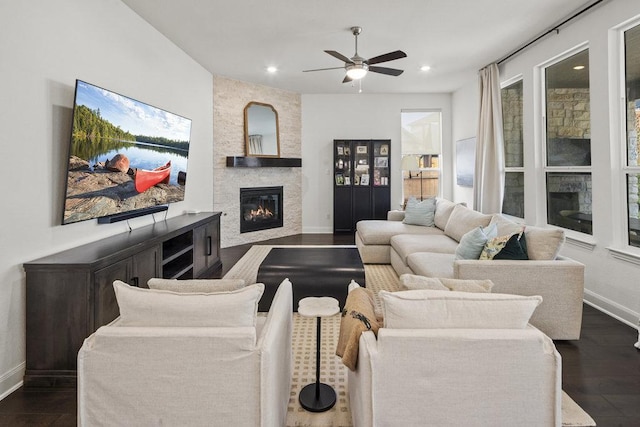 living area featuring recessed lighting, baseboards, a stone fireplace, and dark wood finished floors