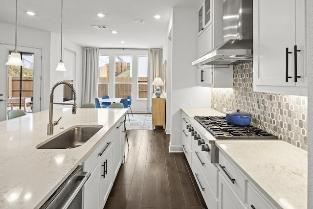 kitchen with backsplash, a sink, dark wood-type flooring, wall chimney range hood, and a wealth of natural light