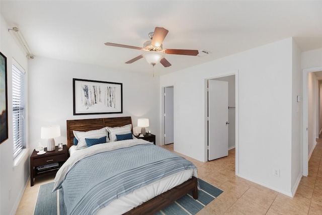 bedroom featuring light tile patterned floors, a spacious closet, baseboards, and ceiling fan