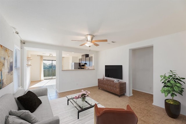 living area with light tile patterned flooring, baseboards, and ceiling fan