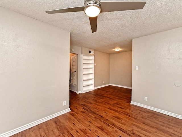 empty room featuring a textured ceiling, baseboards, and wood finished floors