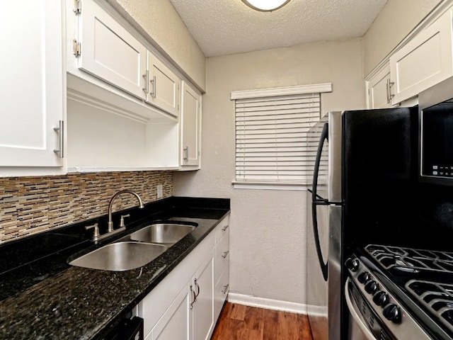 kitchen featuring gas range, white cabinets, and a sink