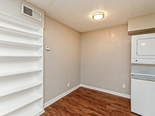 washroom featuring visible vents, stacked washer and dryer, a textured ceiling, wood finished floors, and laundry area