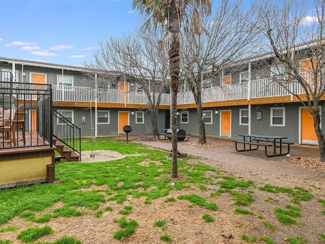 back of property featuring stairway, a patio, and a deck