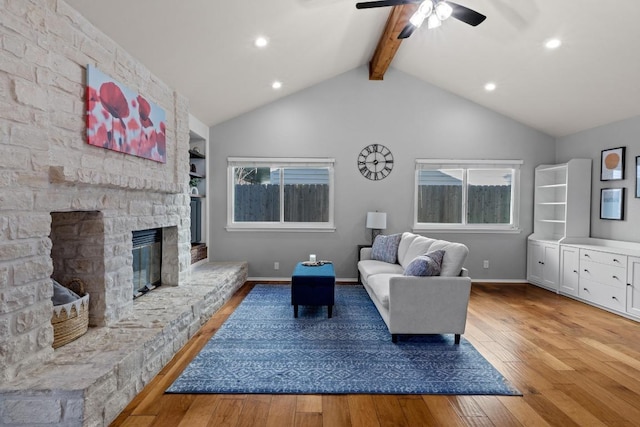 living area with lofted ceiling with beams, baseboards, wood-type flooring, and a fireplace