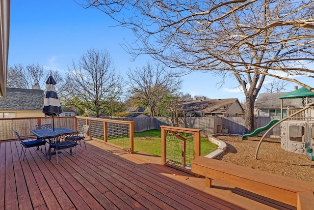 deck featuring a fenced backyard, outdoor dining space, and a playground