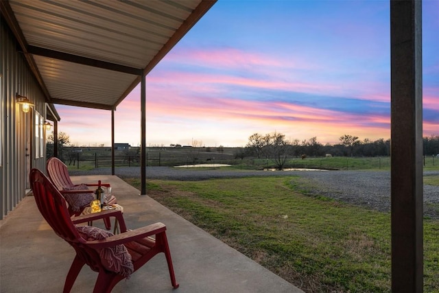 patio terrace at dusk with a rural view and a lawn