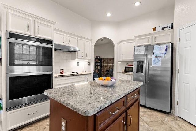 4201 Capri Dr, Killeen, TX 76549 - kitchen with appliances with stainless steel finishes, under cabinet range hood, arched walkways, white cabinets, and tasteful backsplash
