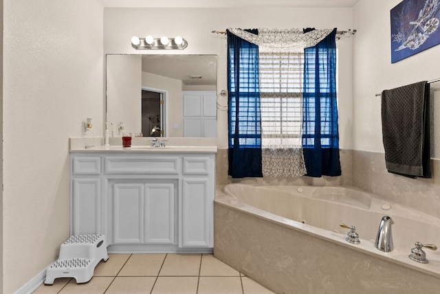 bathroom with a jetted tub, vanity, and tile patterned flooring