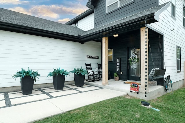 doorway to property featuring covered porch and a shingled roof