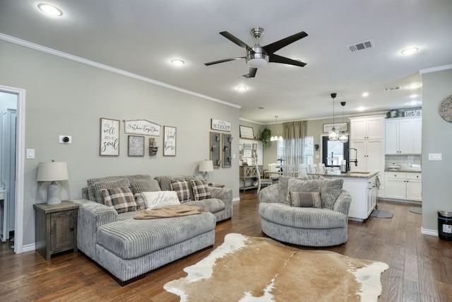 living room with visible vents, dark wood finished floors, crown molding, baseboards, and ceiling fan