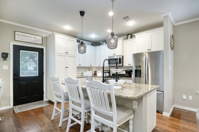 kitchen featuring visible vents, a kitchen island with sink, dark wood-style flooring, stainless steel appliances, and white cabinetry