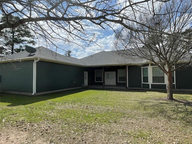 back of property featuring a yard and a shingled roof