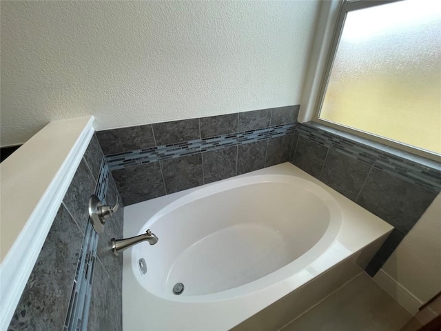 bathroom with a bath and a textured wall