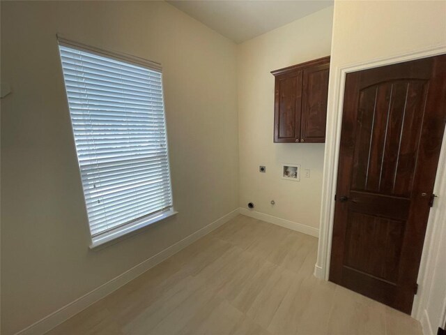 washroom with cabinet space, light wood finished floors, baseboards, hookup for an electric dryer, and hookup for a washing machine