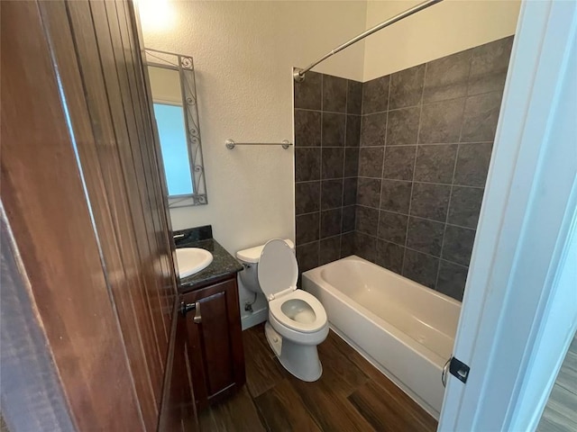 full bathroom featuring toilet, wood finished floors, shower / bath combination, vanity, and a textured wall