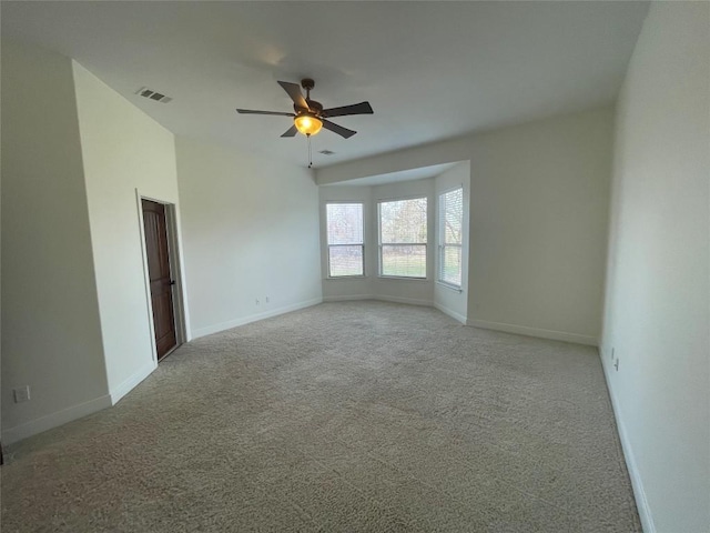 unfurnished room featuring visible vents, baseboards, light colored carpet, and a ceiling fan