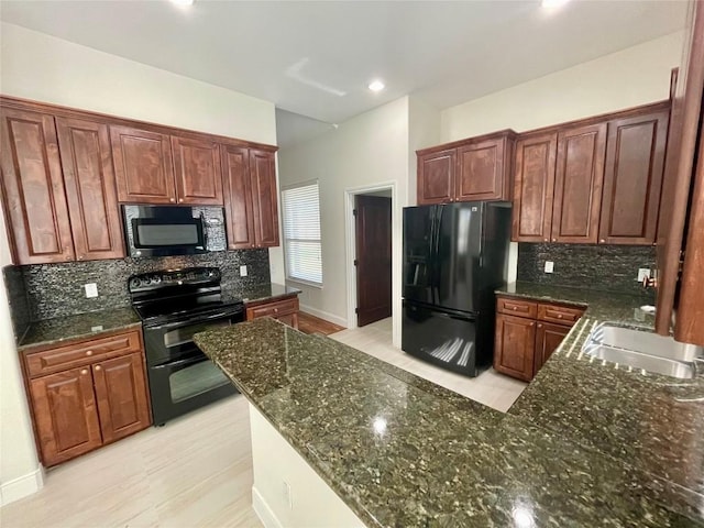 kitchen featuring dark stone countertops, backsplash, black appliances, and a sink