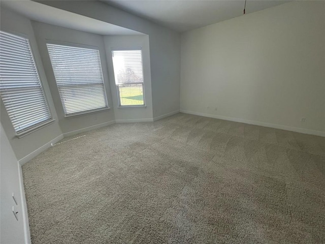 spare room featuring baseboards and light carpet