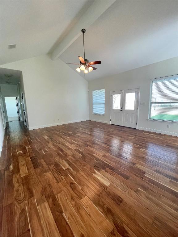 unfurnished living room with visible vents, vaulted ceiling with beams, ceiling fan, baseboards, and wood finished floors